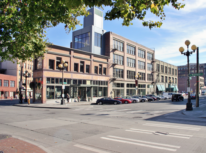 The building at the corner of the block was previously veiled by a solid veneer of plaster and used for storage. The plaster was removed, brick restored, and a new wood storefront milled from old-growth beams salvaged during the renovation was added. The space is now a furniture gallery. The metal box on top contains a stairwell and elevator connecting the adjacent buildings. Photo by Bob Kovalenko.